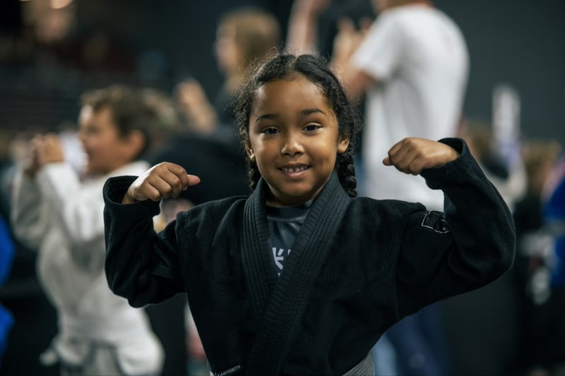 Young girl in a gi flexing at a competition
