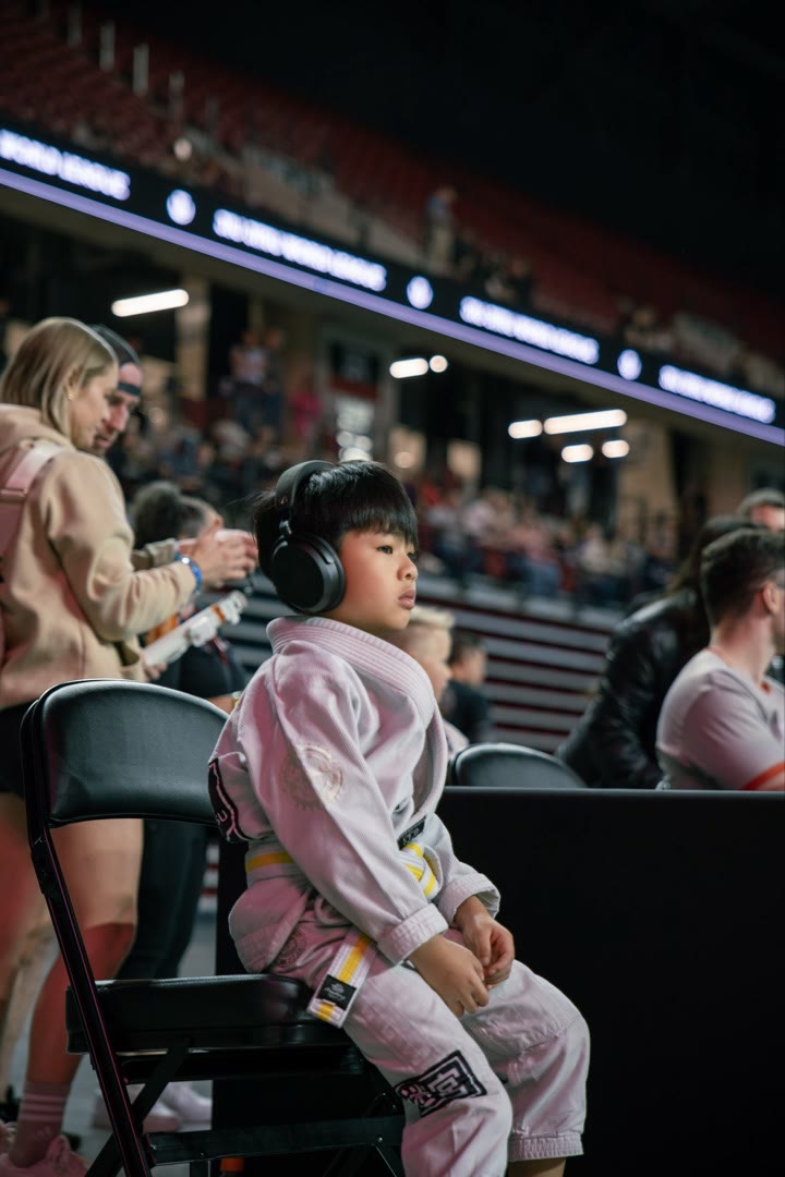 Young athlete in a pink gi waiting at a competition arena